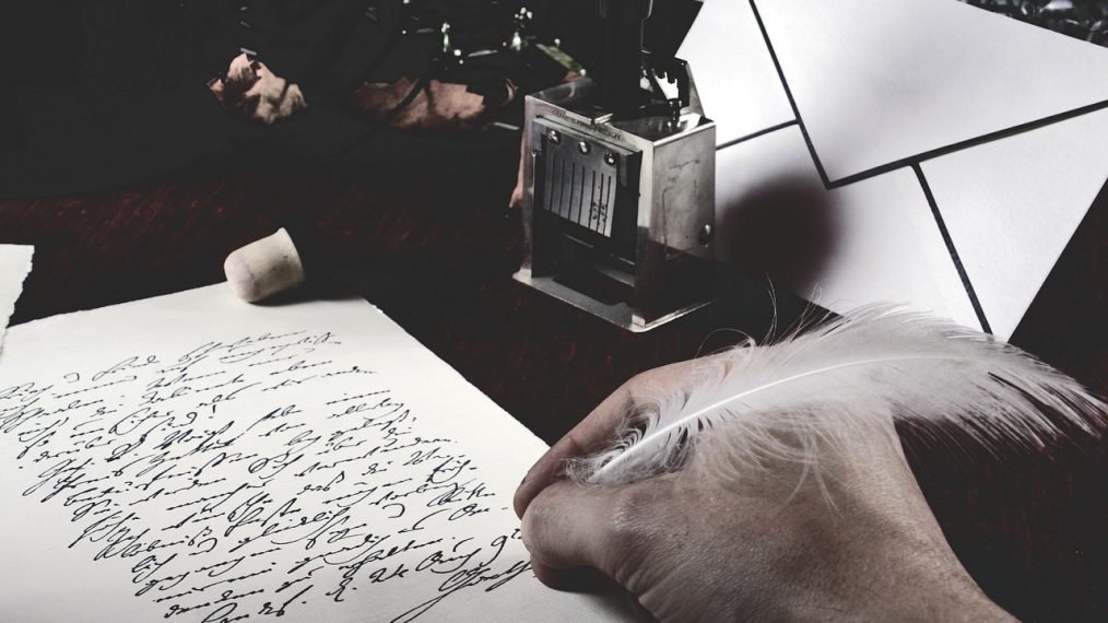 Un mec qui écrit sur du vieux papier avec une plume