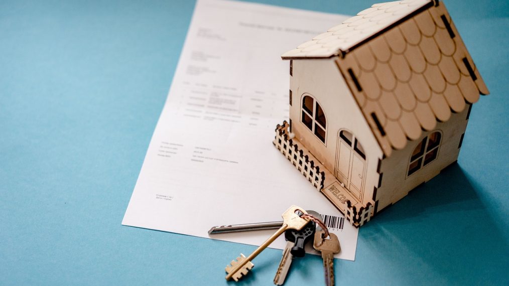 Il y a une petite maison en carton et des clés sur une facture.