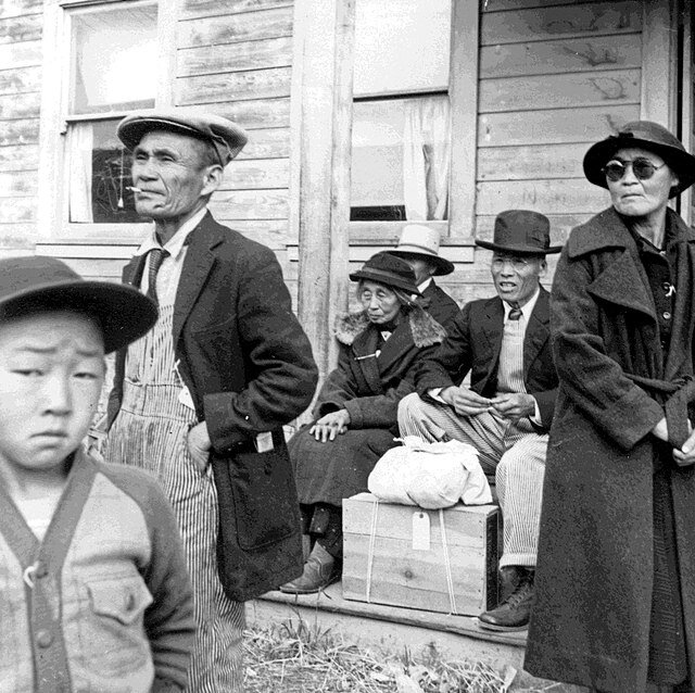 Photographie de Dorothea Lange représentant une famille nippo-américaine attendant un bus en direction d'un camp