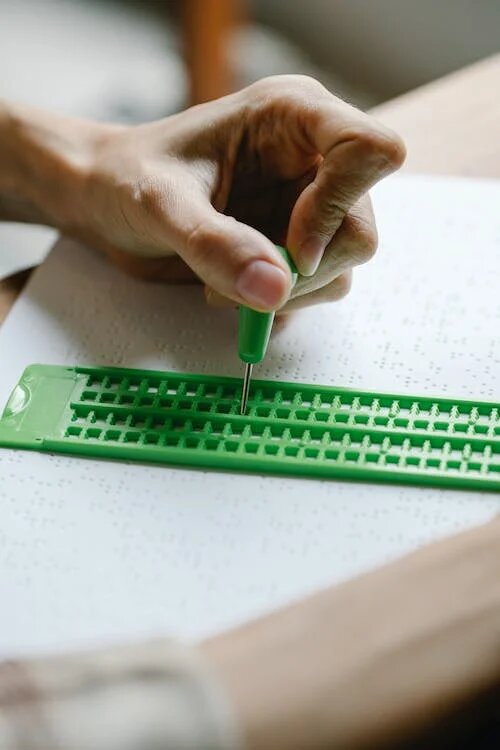 personne qui poinçonne un papier braille