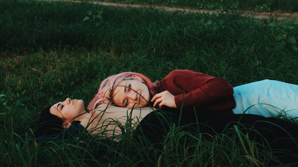 deux femmes allongées dans l'herbe discutant de première fois