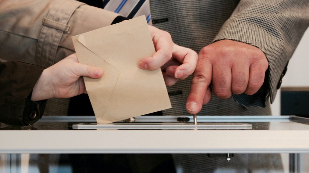 Personnes qui mettent un bulletin de vote dans une urne