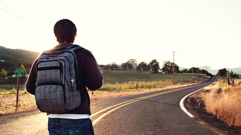 image d'un homme entrain de marcher sur la route et faisant du backpacking