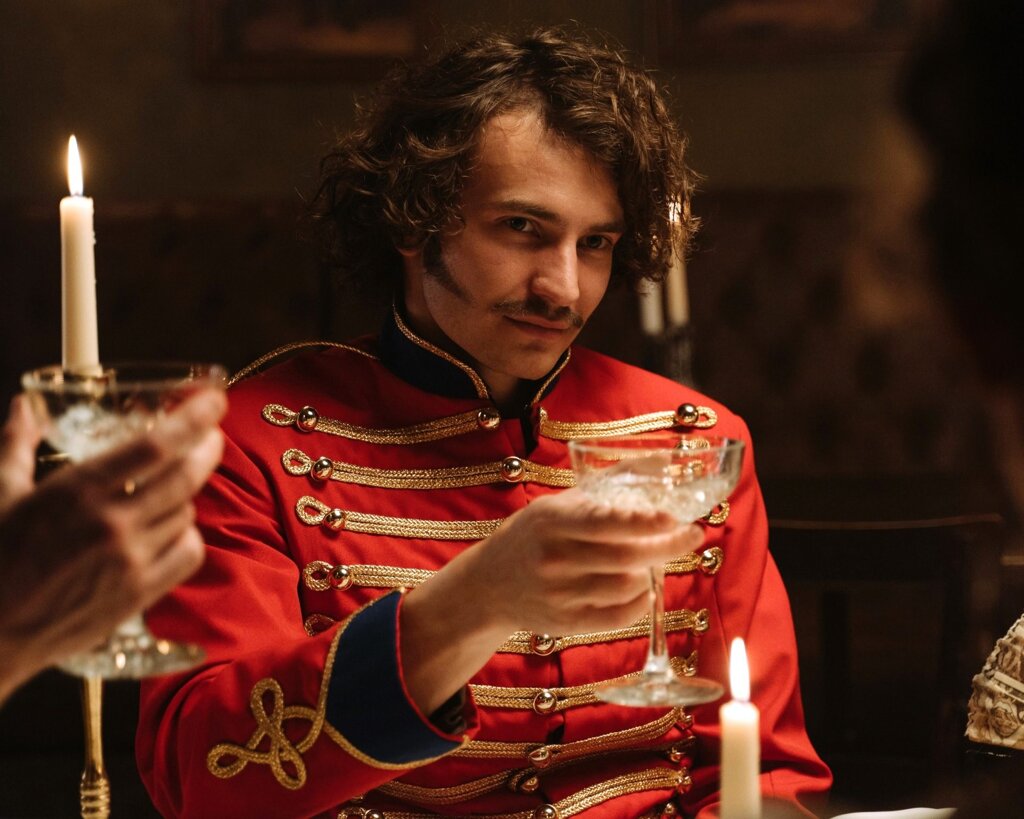 Un aristocrate lève son verre à table pour porter un toast.