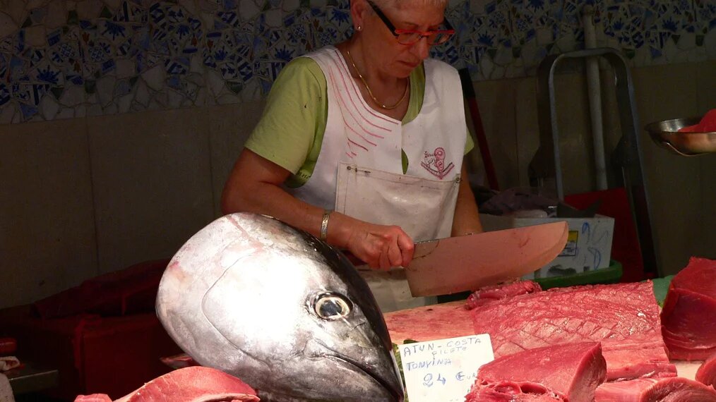 Une poissonnière coupe du poisson sur son stand