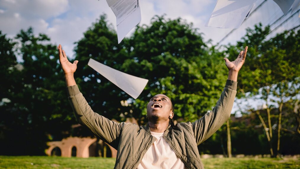 Monsieur qui est content d'avoir réussi ses épreuves et qui jette tous ses papiers en souriant