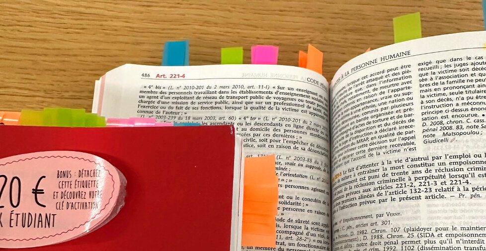 Photo d'un code de droit ouvert avec des post-it dedans. 