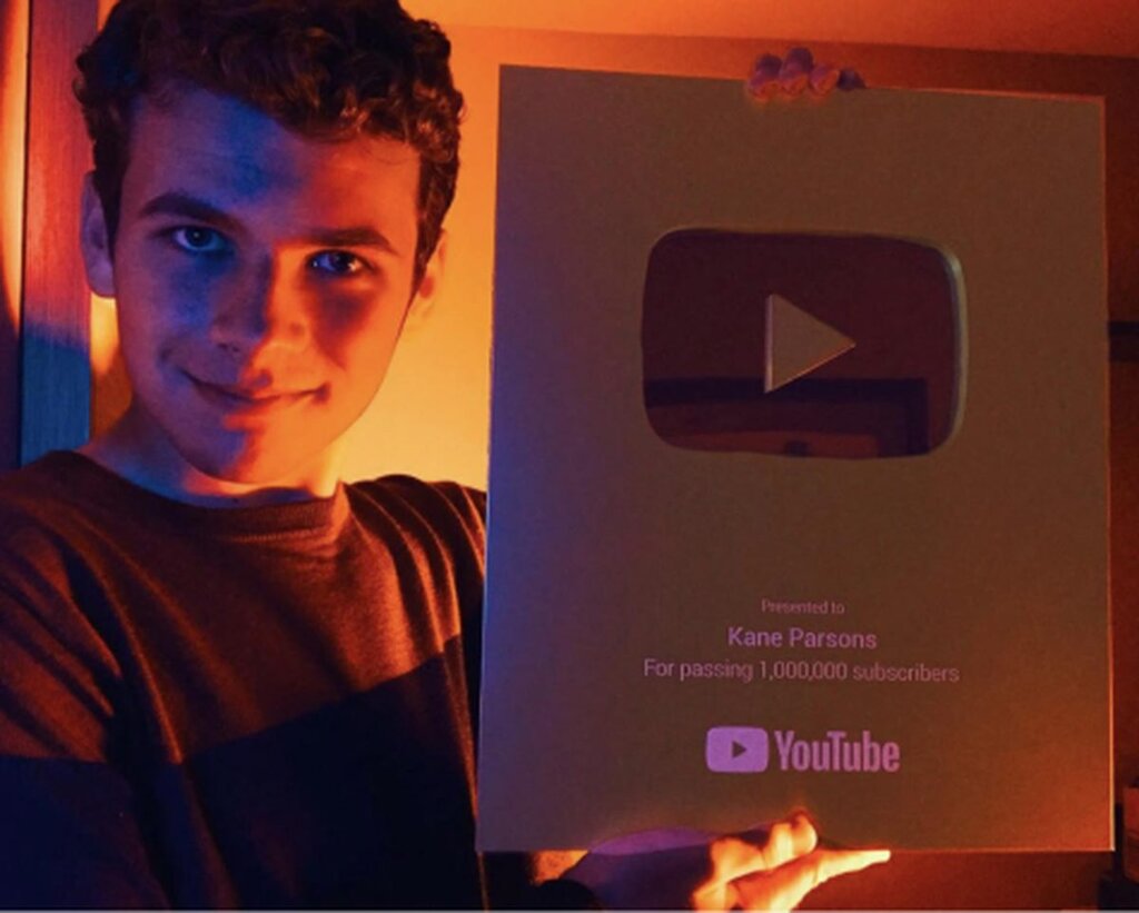 Une photo de Kane Parsons qui tient une plaque Youtube le félicitant pour ses 1 million d'abonnés