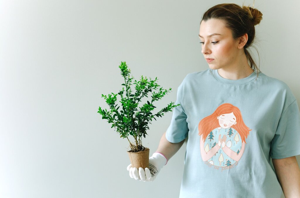 Une fille tient une plante dans sa main.